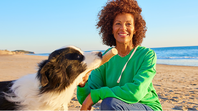Lady playing with her dog on the beach